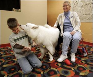 Zach Feasby, 9, tries to read as Nikki sniffs him at the Paws to Read program in Waterville. Nikki s owner is Mary Moser.