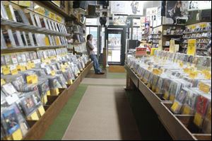 Dave Young, manager of Finders Record & Tapes in Findlay, surveys an empty store yesterday evening during the Super Bowl. He had the TV on, tuned to the game, but said his only interest was watching the Rolling Stones' halftime performance