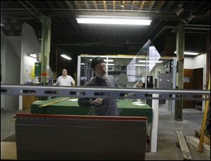 Tim Drouillard places a pane onto a cutting machine in the shop at Avondale Avenue and 11th Street. 