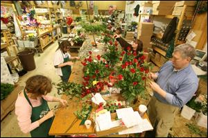 Red roses are the focus as florists and helpers assemble bouquets at the Ken's in Perrysburg. 