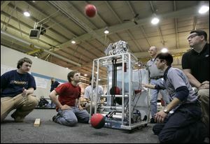 Students from Toledo Technology Academy and their advisors fire test basketball shots with the robot that they've made. They are, from left, Patrick Berning, Andy Breed, Ericka Bilbey, Jim Smith, Josh Hydrew, and Paul Klevann. 