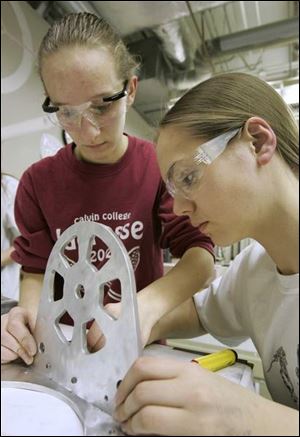 Samantha Mozena and Rachel Becker, from left at left, work on the robot's ball-shooting mechanism. The robotics regional competition starts tomorrow at Eastern Michigan University. The students have been working long hours.
