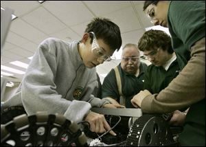 Toledo Technology Academy student Samuel Martin, left, works on the drive train of his team's robot. With him are teacher Tom McNutt and students Patrick Berning and Ericka Bilby, who also attend TTA. 