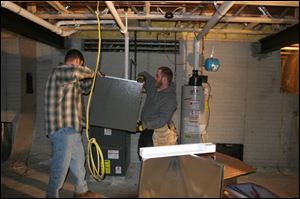 Matthew Lesti, left, and Nick Gangelder install a furnace and air-conditioning unit that replaces the one stolen from a Dold Homes site.