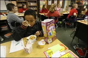 Tyler Piercefield, 10, chows down on his cereal at Liberty Center, which just started its breakfast program this month. Tyler's breakfast bag included milk, juice, and crackers.