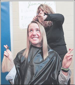 St. Ursula senior Emily Czarka hopes for the best as Jennifer Rippke, a stylist at Camelot Salon, prepares to gather up and shear off 7 inches of her hair as part of a charity event.
