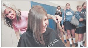 Stylist Theresa Beaverson gives St. Ursula Academy student Lauren Krasniewski a last look at the hair she cut off. Nearly 40 students participated in the charitable event.