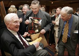 Former state employee Joe Anthony, center, presents former Ohio governor John Gilligan, left, with a photo of a donkey during his 85th birthday party in Columbus.
