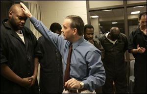 Chaplain Ed Norwood prays with inmate James Braylock during a church service at the jail.