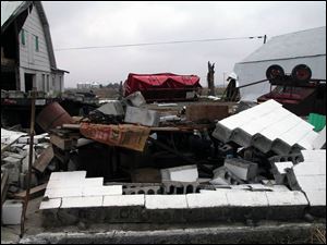 Cement blocks, overturned farm equipment, and a severed tree trunk display the damage done by the tornado that touched down south of Ohio City on Friday evening. On Gale and Jan Baker's farm, every building was damaged, and most of their farm equipment was destroyed. 