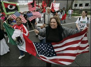 Lucy Dias of Detroit, left, and Yolanda Lopez of Toledo hold conjoined Mexican and American flags during the Farm Labor Organizing Committee's annual march in South Toledo.