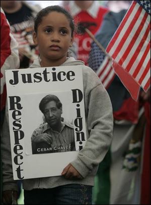 Selena Gilmore, 6, of Detroit displays a poster featuring the late Mexican-American labor activist and United Farm Workers leader Cesar Chavez during the Farm Labor Organizing Committee's annual march in South Toledo for immigrant rights. 