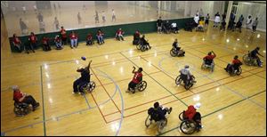 Red-shirted Crash players take on the University of Toledo football team on campus in a wheelchair football contest.