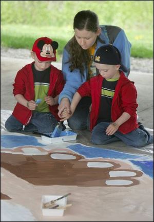 Baby-sitter Sara Wilson lends a helping hand as Jacob and Patrick Marquis contribute to a mural. Tiffin residents are expected to create 45 murals, which will be displayed May 21.