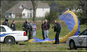 Perrysburg Township police officers investigate the paraglider's crash site on the north side of Roachton Road near Hull Prairie Road. The craft plunged to ground.