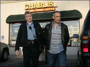 Guirguis Ragheb, right, is led from his store by Toledo police officer Jeff Jackson.