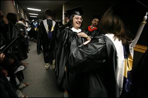 Nicolle Gawlak, right, adjusts the graduation gown of Sarah Long before commencement at the University of Toledo. The women were receiving their master's degrees in applied mathematics. There were more than 2,600 candidates for degrees from UT's seven colleges.