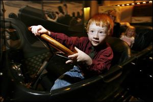 Trent Roseman, 4, of Curtice, Ohio, pretends to steer a 1917 Overland automobile at the Henry Ford Museum.
