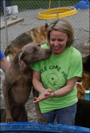 Sheri Plocek of Rover Come Over Doggy Daycare gets up close and personal with one of the affectionate, four-legged customers at her Monclova Township day-care and boarding facility.

