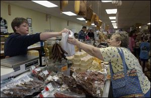 
Janet Reid, left, hands a purchase to Nancy Pratt of London, Ohio, at Cheese Haven near Port Clinton. The shop sells 125 kinds of all-natural cheeses as well as 50 kinds of smoked meats.

