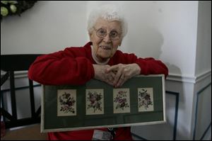 Lois Barrowman, 100, displays some of the crewel work she has crafted over the years. She has also knitted and quilted.
