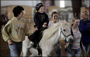 Mitch Sworden, 5, beams as his horse trots along at Vail Meadows Equestrian Center in Oregon. Helping him are Joseph Martinez, 17, from left, Katie Feher, 18, Casey Bursztynski, 13, and therapeutic-riding instructor Peggy Fritz. 