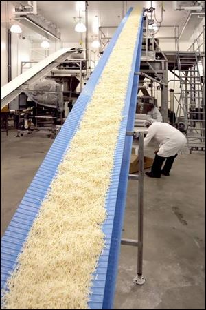 A conveyor belt feeds cheese to chutes that will drop it into bags. 