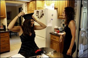 Jenny Kuhn tries on her cap for her 25-year-old sister, Jeana, before Perryburg High School's graduation on June 2. Jenny will attend Miami University in the fall.