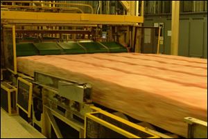 Insulation made of fiberglass, a material that led to the founding of Owens Corning, rolls off a production line.