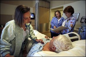 
Tami Good, a respiratory therapist at Bay Park Community Hospital, listens to the lungs of William Dunn, while registered
nurses Cathy Thorn, right, and Sarah Grant read his chart. Ms. Good and Ms. Grant are on the Rapid Response Team.