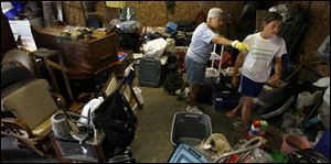 Betty Rhode of Norwalk gives directions to her granddaughter, Sarah Rhode, in sorting through her flood-damaged possessions as she decides what can be salvaged and what can be thrown out. Last week's rains caused Norwalk's reservoir to overflow, resulting in flooding of up to 12 feet in low-lying areas. 