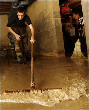 Jerrod Garrett, left, and Dianna Ganzhorn squeegee water from a flooded basement in Collins, Ohio, just east of Norwalk. The teenagers are members of the Young Marines.