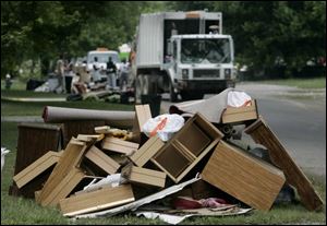 Piles of household items that were ruined in last week's storm await pickup as city crews make their way along Longwood Avenue in Toledo yesterday afternoon. Meanwhile, Gov. Bob Taft's office granted Lucas County emergency status, and city officials pledged continued help to the parts of the city hardest hit by the downpour. 