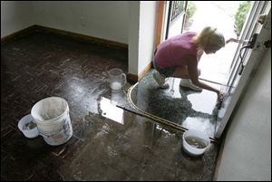 Sandy Wright cleans a home on Longwood Avenue, off Dorr Street. It was among many damaged in last week's storm.