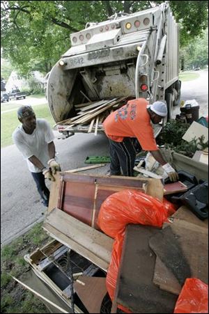 Toledo refuse collectors Michael Lee, left, and Eric Johnson pick up flood-damaged items from homes in South Toledo. 