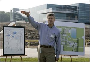 The nearly complete Owens-Illinois headquarters building in Perrysburg s Levis Development Park gleams in the background as real estate manager Frank Butler describes the facility that is due to open in August. Lead architect John Hrovat describes the $20 million structure as  sleek, contemporary, and humble.  