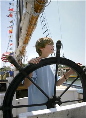 Sebastian Lilge of Dearborn, Mich., gets his turn to see what it's like to man the helm of the schooner Madeline, which is tied up at the Meigs Street Pier in Sandusky.