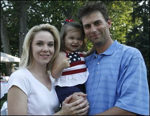 RED, WHITE, AND BABY BLUE: Katrina and Daniel Trombley hold daughter Isabella, 21 months, who shows off her patriotism at the Toledo Country Club picnic.