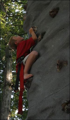 CLIMBING THE WALL: Keegan Hannan, 7, makes his way up the climbing wall during the Fourth of July picnic at Toledo Country Club.