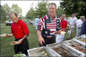 HEAPING HELPINGS: Dave Jagodzinski carries off two plates and Tom Tillander dives into the trays at the Belmont Country Club Fourth of July party. Although it seems that the food was nearly gone, the trays were refilled and Mr. Tillander had his share.