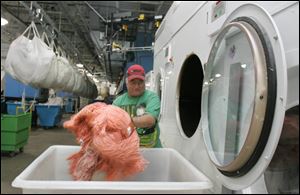 Marshall Hill unloads freshly laundered industrial-size mop heads from a giant dryer.