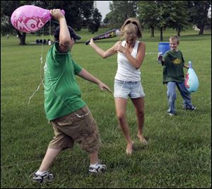 Mikey Epstein, left, and Mark Farley attack Ally Falter with inflatable bats and Silly String during Perrysburg's Star-Spangled Banner Celebration at Fort Meigs State Memorial Park. Family activities were featured before the fireworks display. 