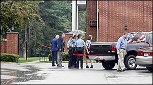 Toledo-area law enforement officers survey the murder scene in the parking lot of Salem West apartments at 2905 Tremainsville Rd. in Toledo yesterday afternoon. Susan Hichborn, 39, was killed with several shots of a handgun by Lawrence Hichborn, from whom she was seeking a divorce and a temporary protective order.