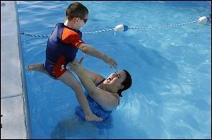 Katie Wagner of Perrysburg catches her son Nathan, 3, as he jumps in the pool at Perry Lake Village apartments. Willys Pool in West Toledo had to turn swimmers away by midafternoon.