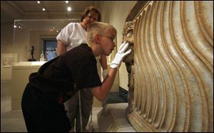 Taylor Adolph, 9, examines a lion's head carved on a Roman sarcophagus as docent Mary Ann Boesel looks on.