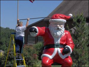 A worker freshens up the paint on the statue of Santa that stands outside Santa's Lodge hotel in Santa Claus, Ind.
