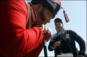 Drum major John Oien, foreground, rests while Rob Trumbull smokes a pipe at Fort Meigs. The men were part of the weekend-long Drums Along the Maumee re-enactment at the fort, which featured four fife and drum corps.