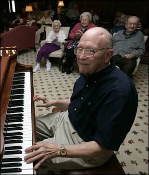 Olan Snavely, an Alzheimer's volunteer, tickles the keys at Sunset House before his appreciative listeners.