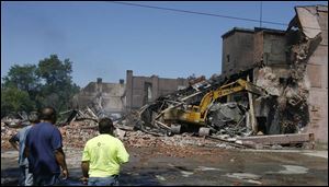 A piece of wrecking equipment claws its way into the remains of the burned-out warehouse.