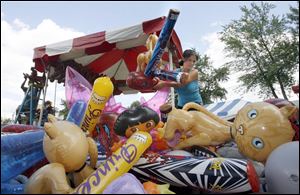 Liz Calton sets up a booth at the Seneca County Fair for Michael's Amusements. The fair in Tiffin runs through July 31.